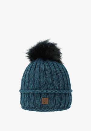 Teal knitted beanie with ribbed texture, foldable cuff, and black faux fur pom-pom on top. Features a small brown leather logo patch.