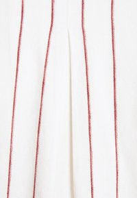 Weißer Stoff mit roten vertikalen Streifen, ausgestattet mit einer feinen strukturierten Oberfläche und einem Mittelfalte, entworfen für einen lockeren Sitz.