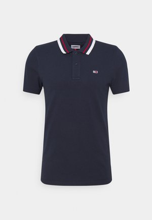 Navy blue short-sleeve polo shirt with white and red striped collar and small rectangular logo on the left chest.