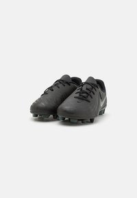 Schwarze Fußballschuhe aus strukturiertem Synthetikmaterial, mit niedrigem Profil, Schnürsenkeln und Gummistollen für Halt.