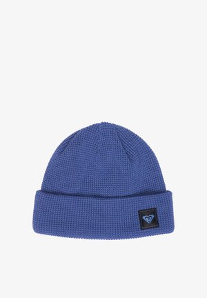Bonnet tricoté bleu avec revers et une petite étiquette noire arborant un logo en forme de cœur sur le revers.