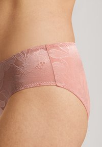 Krajkové boxerky v jemně růžové barvě s květinovým vzorem, s bezešvými okraji a strukturovanou tkaninou. Středně vysoký střih s hladkým zakončením.