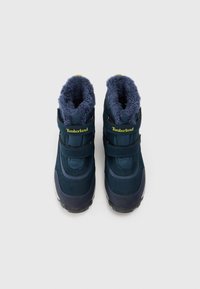 Stivali Timberland blu scuro con un morbido rivestimento in pelliccia. Presentano cinturini regolabili, una suola robusta e un design della caviglia imbottito.