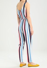 Randig jumpsuit med stor scooped rygg, prydd med vertikala blå, rosa och vita ränder. Mjuk tyg, tapered ben och bältesdetalj i midjan.