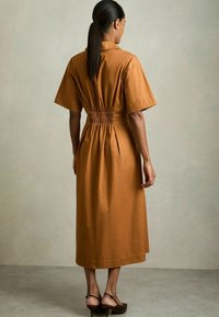 Bruine jurk met kraag, korte mouwen, elastische taille en midi-lengte. Glad stof, minimalistisch ontwerp en effen kleur.