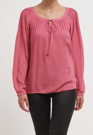 Blusa rosa a maniche lunghe con scollatura rotonda, dettagli testurizzati sulle spalle e un fiocco con una decorazione a perla sul davanti.
