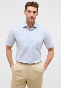 Korte mouwen overhemd in lichtblauw met witte verticale strepen, voorzien van een borstzak en een standaard kraag, gecombineerd met beige broeken.