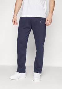 Navy blue sweatpants made of soft cotton with a relaxed fit. Features a small embroidered logo on the side and elastic cuffs at the ankles.