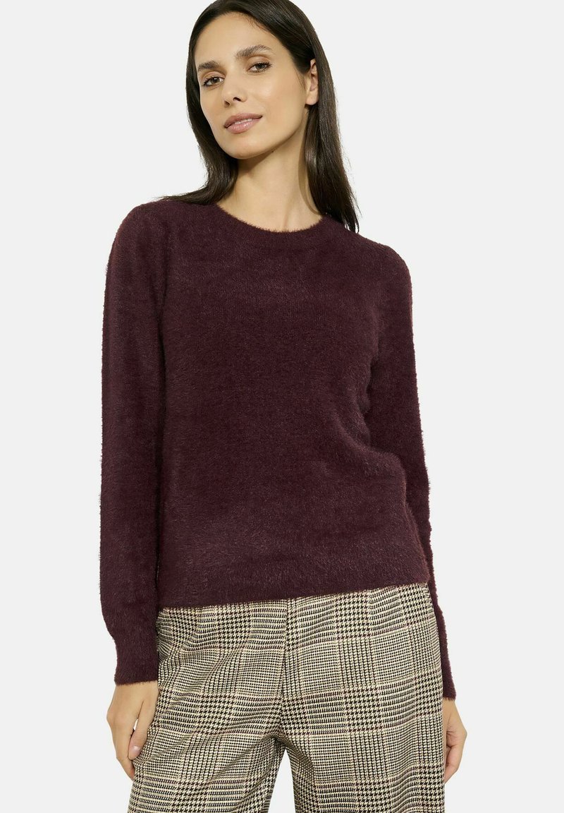 Maglione borgogna peloso con maniche lunghe e colletto a costine, abbinato a pantaloni a quadri a vita alta in beige e nero.