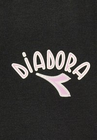 Tessuto nero con la scritta "Diadora" in caratteri bianchi e rosa grassetto e stilizzati, accompagnata da un accento curvo rosa. Superficie testurizzata a coste.