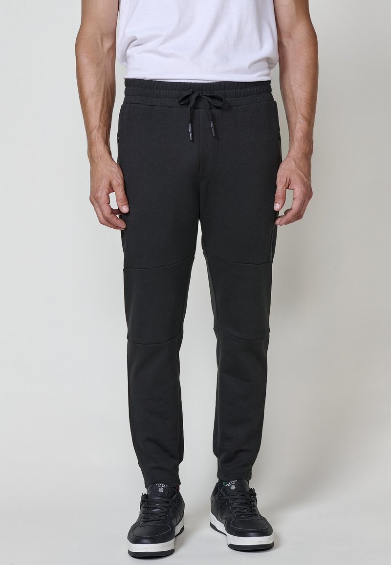 Dunkelgraue Sweatpants aus einem Baumwollmix. Sie verfügen über einen Kordelzug an der Taille, Seitentaschen und Paneeldetails an den Beinen.