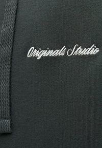 Mørkegrå sweatshirt med broderet teksten "Originals Studio" i hvid, lavet af et glat, struktureret stof og med hætte.