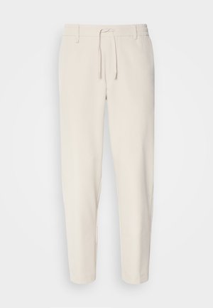 Helle-beige Hosen mit einer schmal zulaufenden Passform, elastischem Bund und Kordelzug. Glattes Material mit seitlichen Taschen und genähten Säumen.