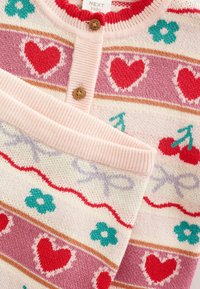 Knopf-zu-Strickpullover in Rosa und Cremetönen, mit Mustern aus Herzen, Blumen und Kirschen, sowie geripptem Ausschnitt und Bündchen.