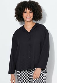 Schwarzes Button-up-Hemd mit Kapuze, langen Ärmeln und lockerer Passform. Es zeichnet sich durch glattes Material und ein dezentes Schachbrettmuster im unteren Bereich aus.