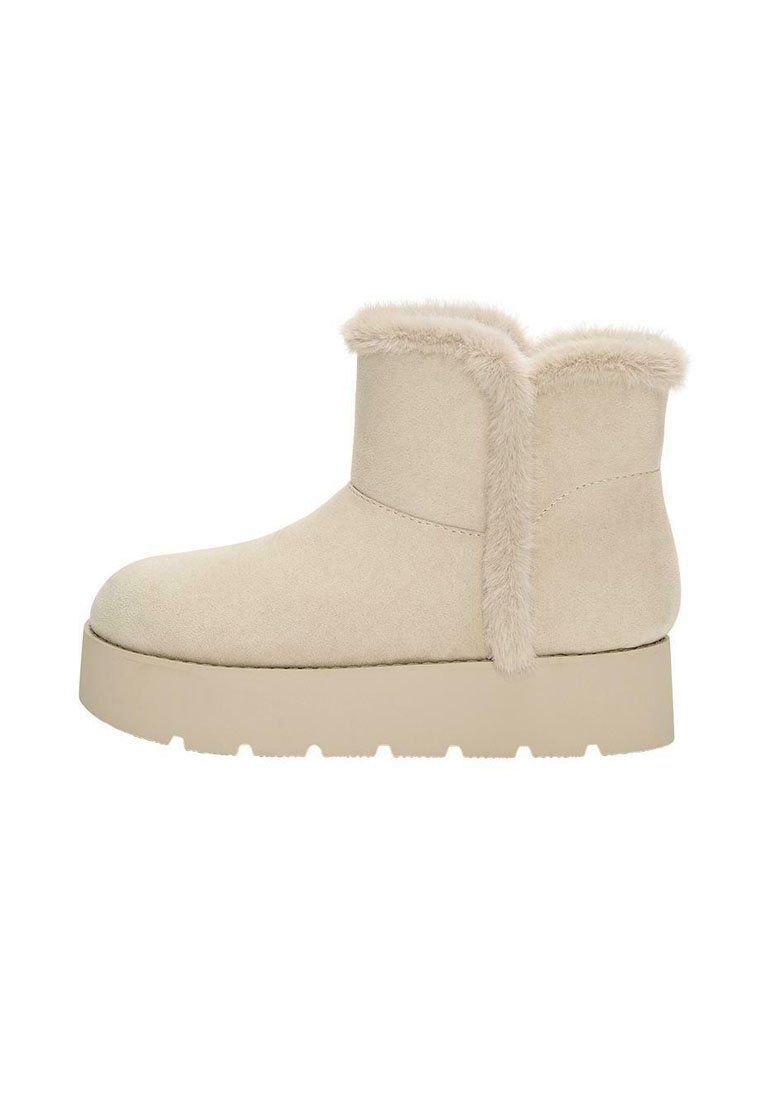 Stivaletti beige in suede, dotati di un morbido collare in finta pelliccia, punta arrotondata e una suola piatta spessa e testurizzata.