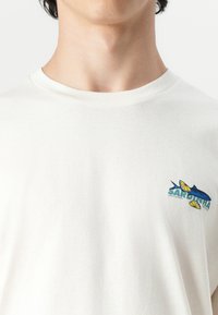 White cotton t-shirt featuring a multicolored graphic with a fish and lemon design, round neckline, and short sleeves.