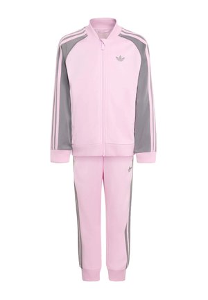 Jasnoróżowy i szary dres dziecięcy Adidas z bluzą na zamek, paskami na rękawach oraz dopasowanymi spodniami z bocznymi paskami i logo.