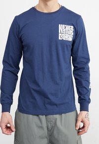 Marinblå långärmad t-shirt i bomull. Har en framsidestextgrafik "NEVER STOP EXPLORING" i vitt och ribbad rund halsringning.