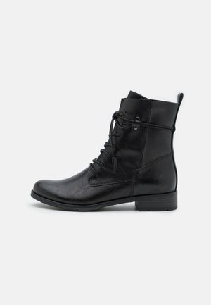 Sort læderankelstøvle med rundet tå, lav hæl, snørelukning foran og trækstrop på bagsiden på hvid baggrund.