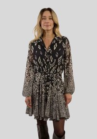 Schwarz-weißer, gemusterter Kleid mit langen Ärmeln, einem Kragen und einem gerafften Rock. Verfügt über eine Bindegürtel und eine strukturierte Stoff.