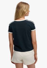 Marineblauw katoenen T-shirt met korte mouwen, een crèmekleurige kraag en zijstrepen, gecombineerd met lichtbeige korte broek, met een losse pasvorm.