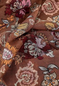 Tessuto floreale marrone con grandi fiori vivaci nelle tonalità di rosa, arancio e bianco, arricchito da foglie dettagliate e una trama morbida e tessurizzata.
