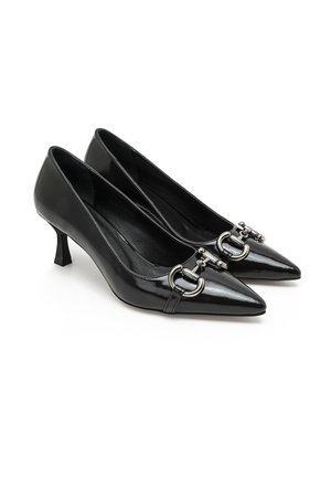 Black patent leather pumps with a pointed toe, small block heel, and silver buckle detail on the strap. Smooth texture and sleek design.