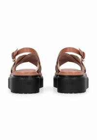 Sandales en cuir marron avec bride arrière ajustable, semelle compensée et texture en caoutchouc. Logo de la marque "LIU•JO" embossé sur le talon.