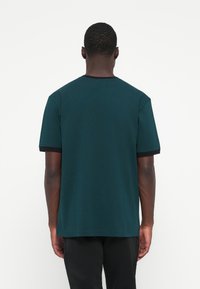 Teal bomulds T-shirt med rund hals og korte ærmer, med sort kantalong ved kraven og ærmerne, ensfarvet bagdesign.