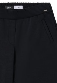 Pantalon noir avec une large ceinture élastique, doté d'une poche avant et d'un petit logo métallique. Fabriqué en tissu lisse et léger.