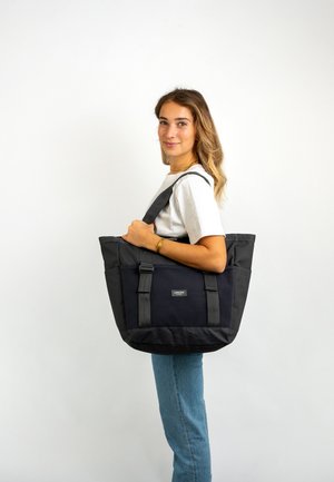 Sac fourre-tout noir avec des poignées grises, présentant une surface texturée et un logo à l'avant. Conçu pour la polyvalence et la fonctionnalité.