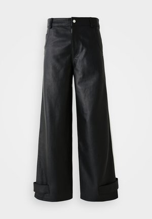 Zwarte leren broek met brede pijpen en een gladde textuur, riemlussen, voorkantzakken en boorden bij de enkels. Voorzien van een drukknoopsluiting aan de voorkant.