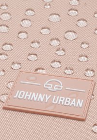 Vízálló rózsaszín textil, kiemelkedő vízcseppekkel és egy fehér "JOHNNY URBAN" márkájú logóval az alsó bal sarkában.