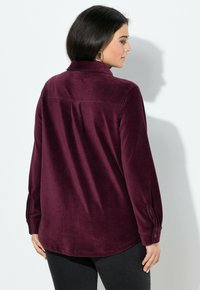 Burgundská košile na knoflíky s límečkem, dlouhými rukávy a měkkou, sametovou texturou, vybavená zadním skladem pro snadný pohyb.