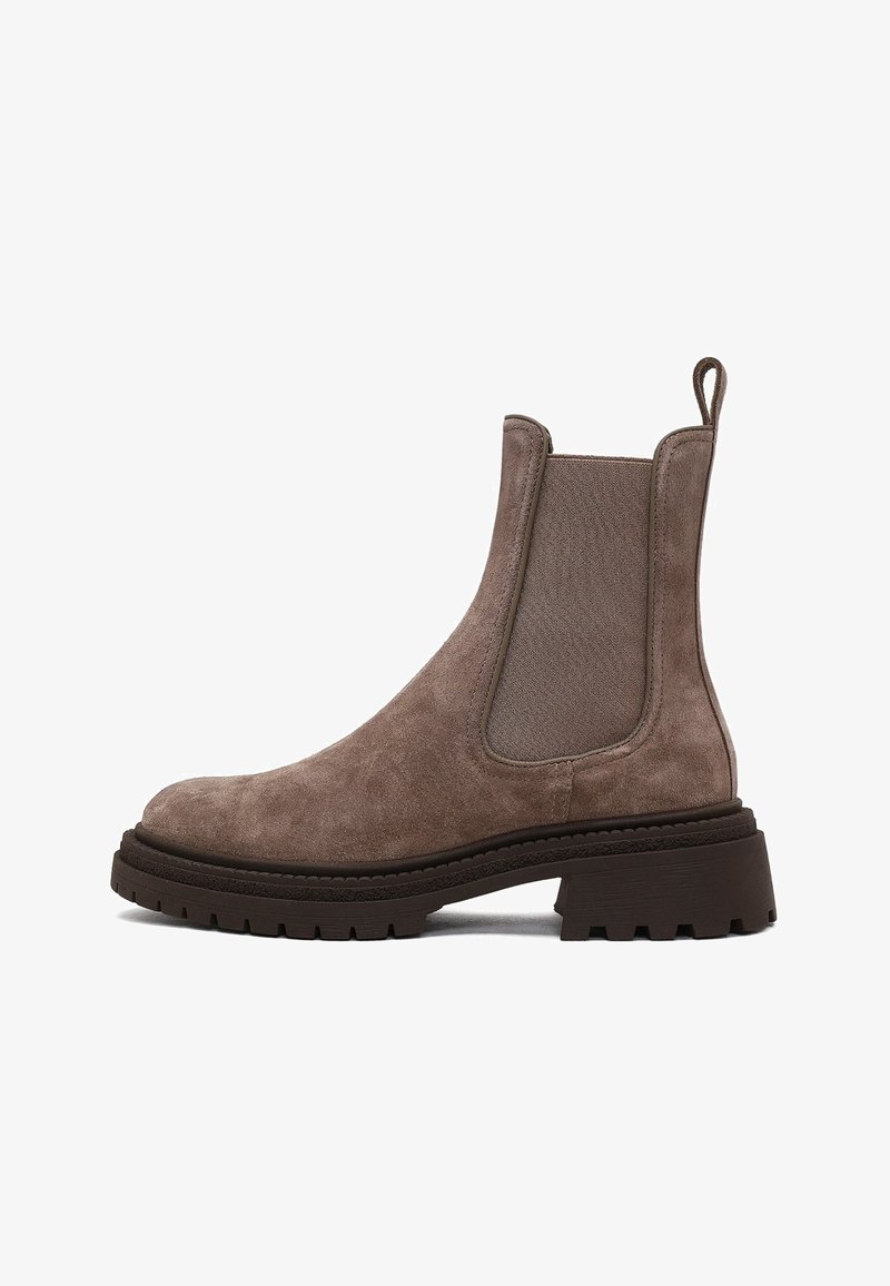 Botte Chelsea en suède marron avec panneaux élastiques sur les côtés, tirette, semelle en caoutchouc épaisse et design texturé. Bout arrondi et silhouette hauteur cheville.