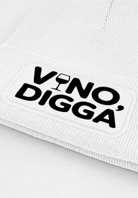 White knitted beanie with a rectangular black patch featuring the text "VINO DIGGÁ" and a wine glass graphic in the center.