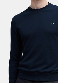 Maglione a maglia blu navy con collo rotondo e maniche lunghe. Presenta un piccolo logo bianco sul petto sinistro e polsini e orlo a coste.