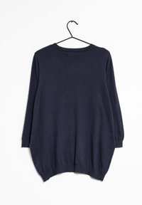 Un haut à manches longues bleu marine en tissu doux, avec un col rond et un ourlet arrondi et ample. Suspendu à un cintre noir.