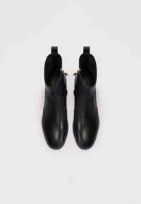 Bocanci din piele neagră până la gleznă, cu un finisaj neted, închidere cu fermoar pe lateral, vârf rotunjit și design minimalist.