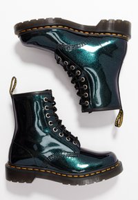 Bottes de cheville à lacets en matériau pailleté teal brillant, avec des accents noirs, des semelles en caoutchouc épaisses et un surfilage jaune distinctif.