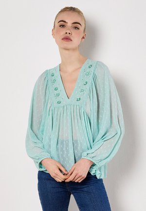 Helles teal-blaues Blusentop aus transparenter Stoff, mit V-Ausschnitt, langen Puffärmel, gepunkteter Textur und floralen Stickereien entlang des Ausschnitts.