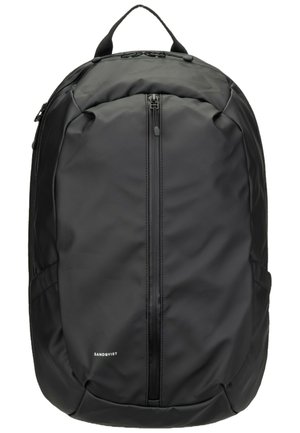 Schwarzer Sandqvist Rucksack mit vorne liegender vertikaler Reißverschlusstasche und gepolstertem Griff oben.