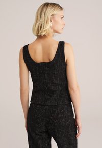 Črna brezrokavna majica z zaobljenim izrezom, teksturirano blago z diskretnimi kovinskimi niti in oprijet kroj.