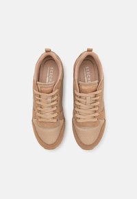 Baskets couleur sable en mesh et daim, bout rond, lacets plats et semelle en caoutchouc texturée. Détails du logo sur la languette et le côté.