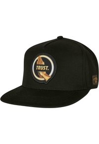 Căciulă de baseball neagră cu vizieră plată, având un patch circular cu un logo ce prezintă mâini și cuvintele "TRUST." pe el, plus un mic etichetă maro pe lateral.