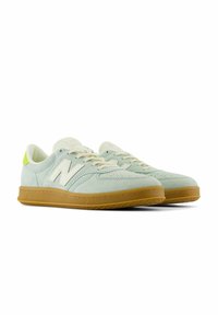 Miętowo-zielone zamszowe sneakersy z białym logo, kremowymi sznurówkami i gumową podeszwą. Posiadają okrągły czubek oraz perforacje dla lepszej wentylacji.