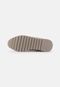 Beige rubber shoe sole with a textured surface and horizontal grooves for grip, featuring a slightly raised heel.