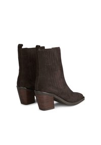 Botas de tobillo de ante marrón con punta afilada y detalles acanalados en el lateral, con tacones apilados que presentan un patrón a rayas.