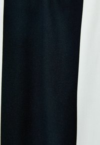 Tekstiili, jossa on sileä pinta ja kontrastoivat mustat ja valkoiset osiot, esittäen pystysuoran ja terävärajaisen jaon.